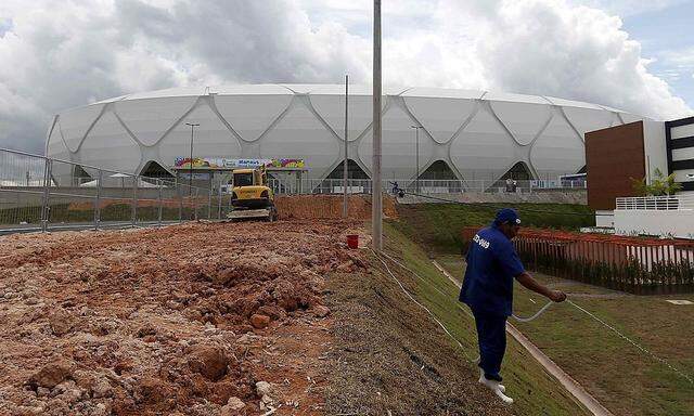 A worker waters the field outside the Arena da Amazonia stadium in Manaus ahead of the 2014 World Cup 