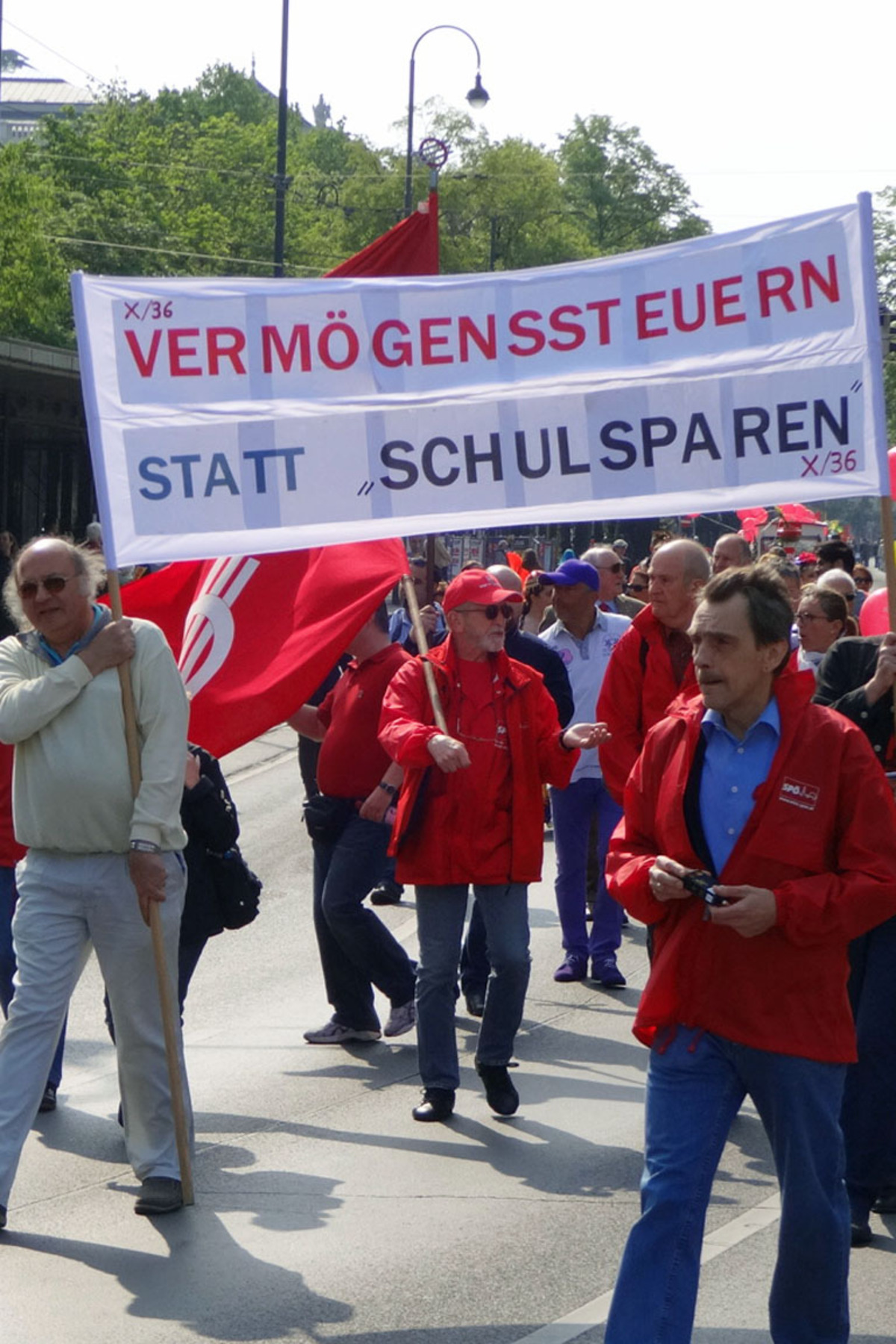 Keine Bürsten, dafür ein Transparent haben diese Genossen mitgebracht. Ihr Anliegen: „Vermögenssteuern statt Schulsparen."