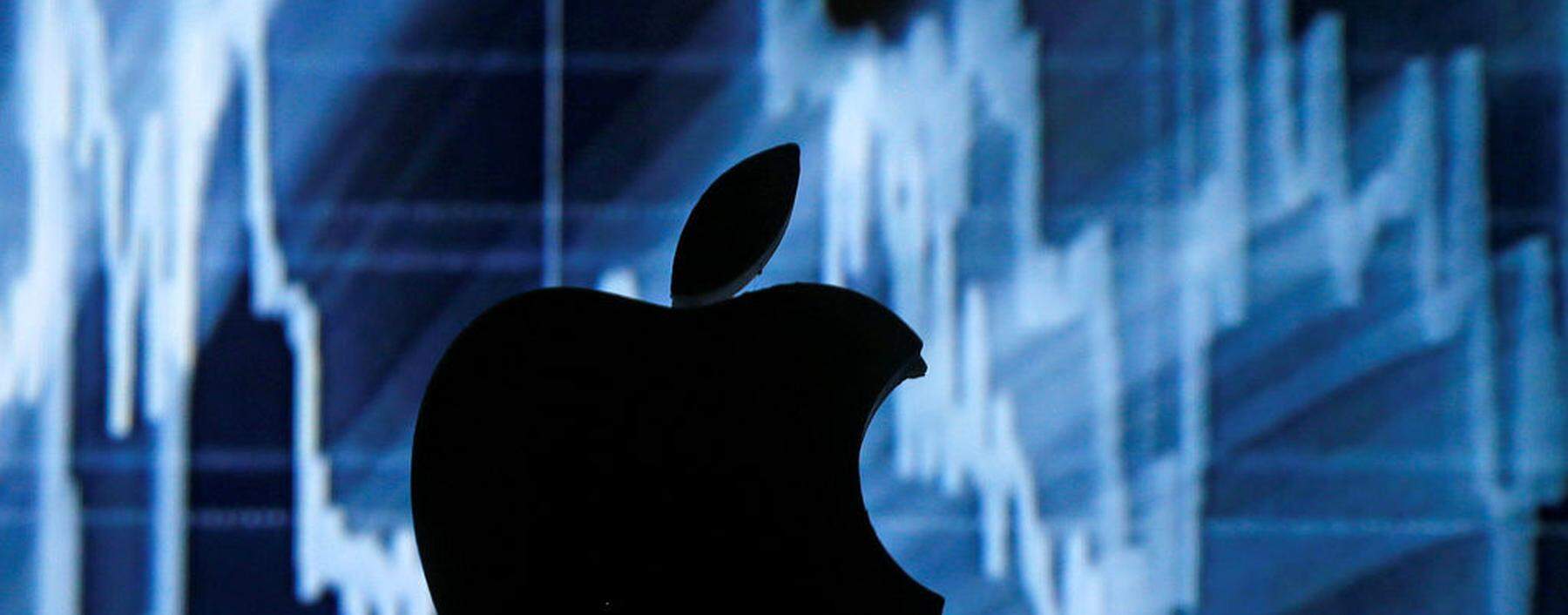 A 3D printed Apple logo is seen in front of a displayed stock graph in this illustration taken