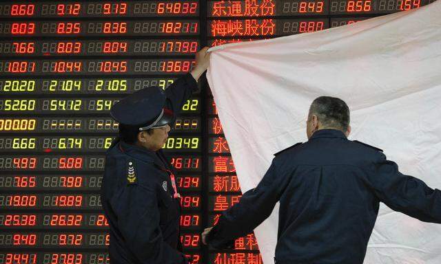Security guards cover a screen displaying stock information in preparation for a lecture after the market closed at a brokerage in Huaibei