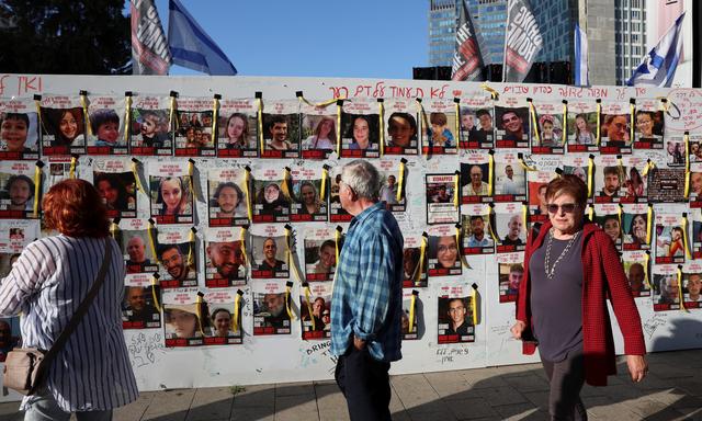 An einer Wand kleben zahlreiche Bilder von verschleppten israelischen Geiseln. 