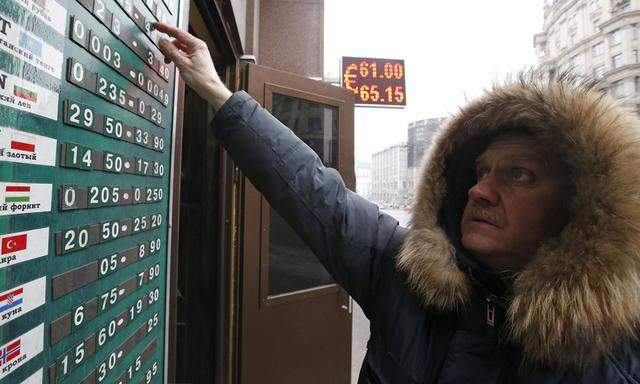 An employee changes figures on a board showing currency exchange rates in Moscow