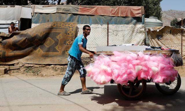 A street vendor sells cotton candy at a camp for Syrian refugees near the town of Qab Elias