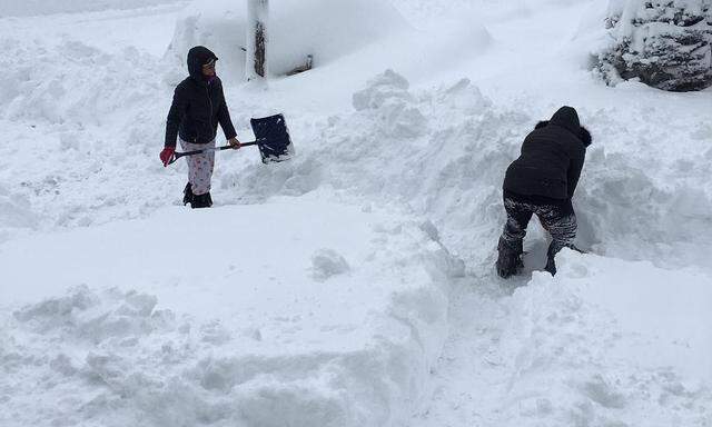 People dig out the path by their house after the record snowfall in Erie