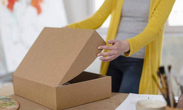 Woman unpacking cardboard box at home studio model released Symbolfoto property released EIF00552