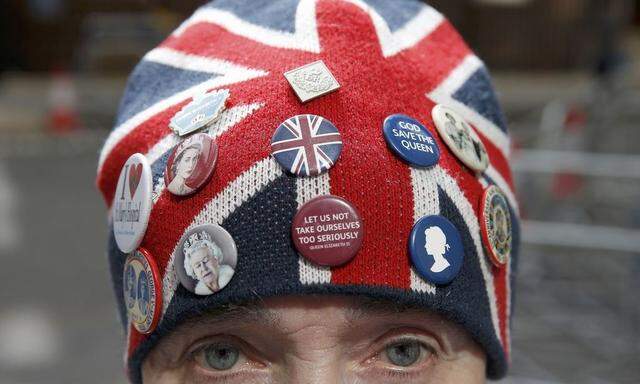 A fan of the royal family wears a union jack hat decorated with badges outside the Lindo Wing of St Mary's hospital in London