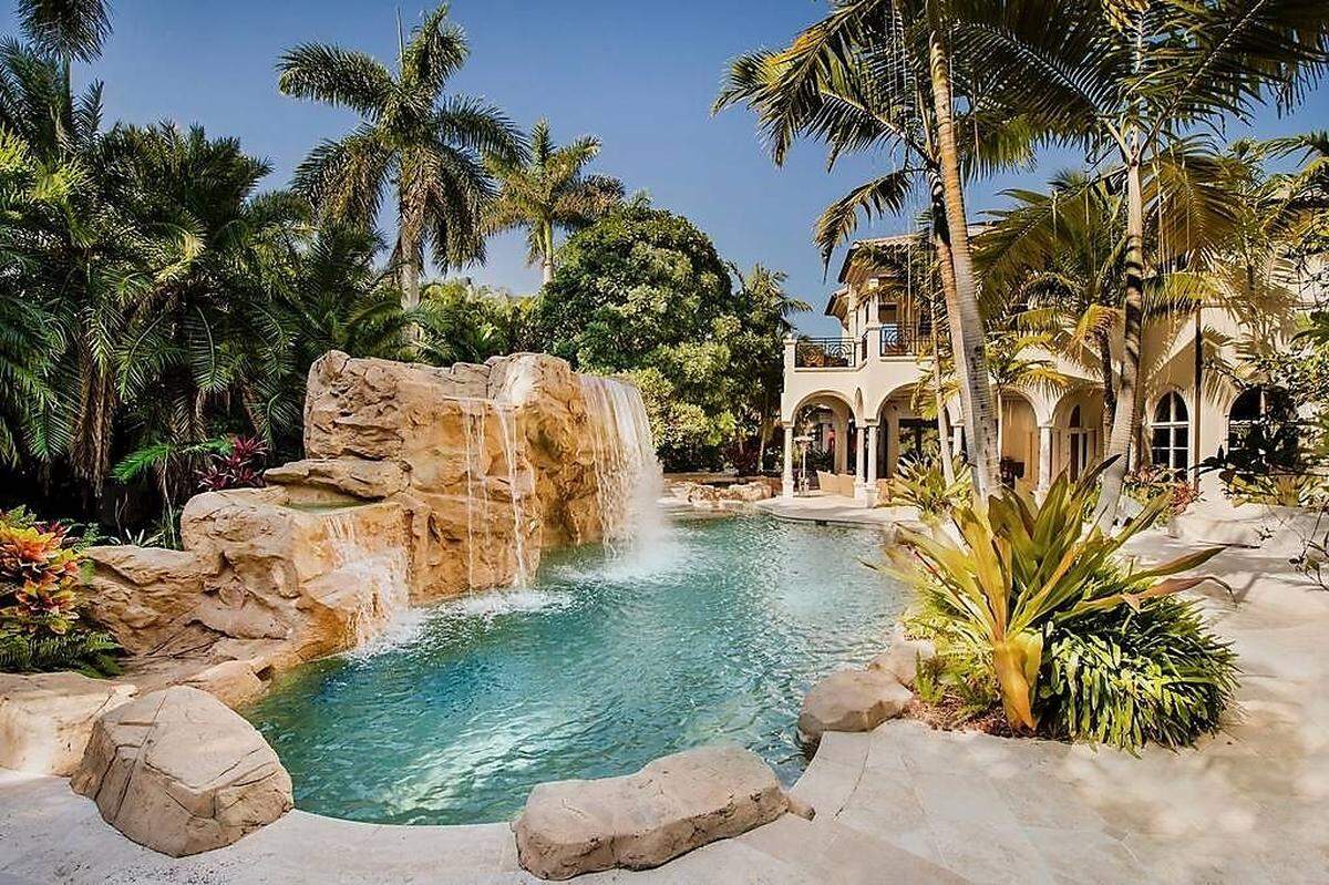 Ein klassisches Layout wählten die Gestalter dieser Villa im US-Sonnenstaat Florida für den Pool der Anlage: Palmen, Naturstein, Wasserfall.