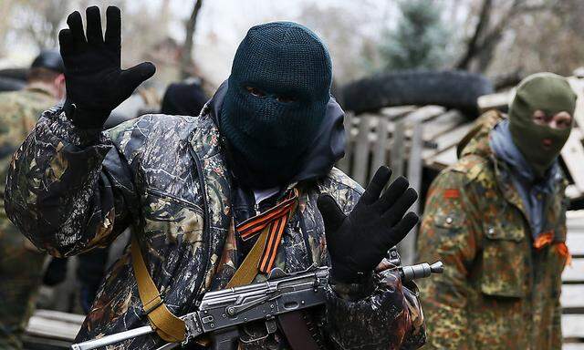 An armed man gestures in front of the police headquarters in Slaviansk