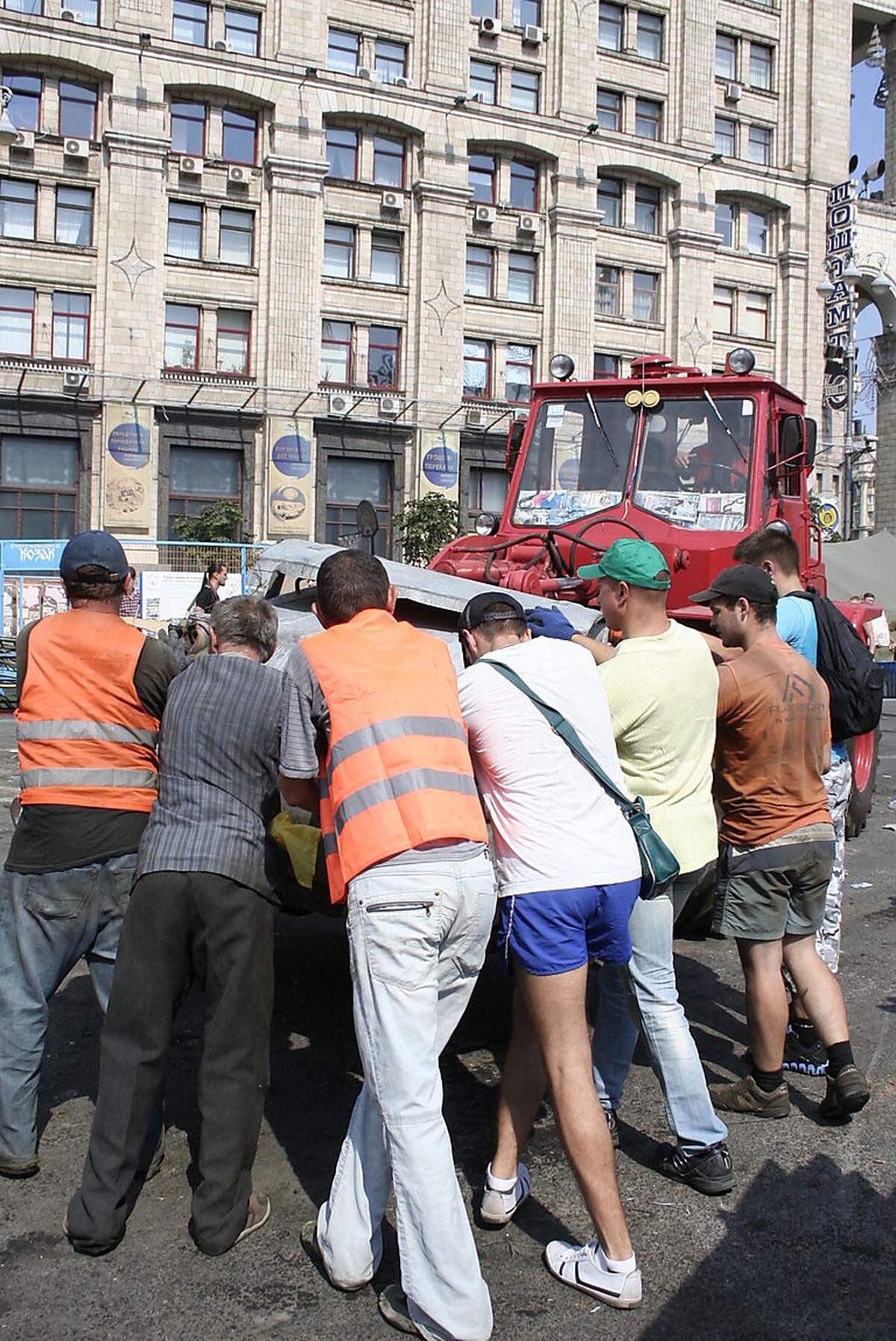 Mit vereinten Kräften hieven diese Männer einen Müllcontainer auf die Traktorschaufel. Viele Bürger beteiligen sich an der Putzaktion, zu der Bürgermeister Vitali Klitschko aufgerufen hat.