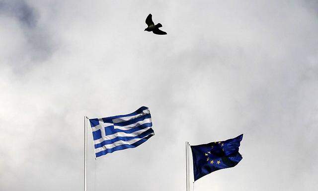A Greek (L) and an EU flag flutter as a pigeon flies past in Athens