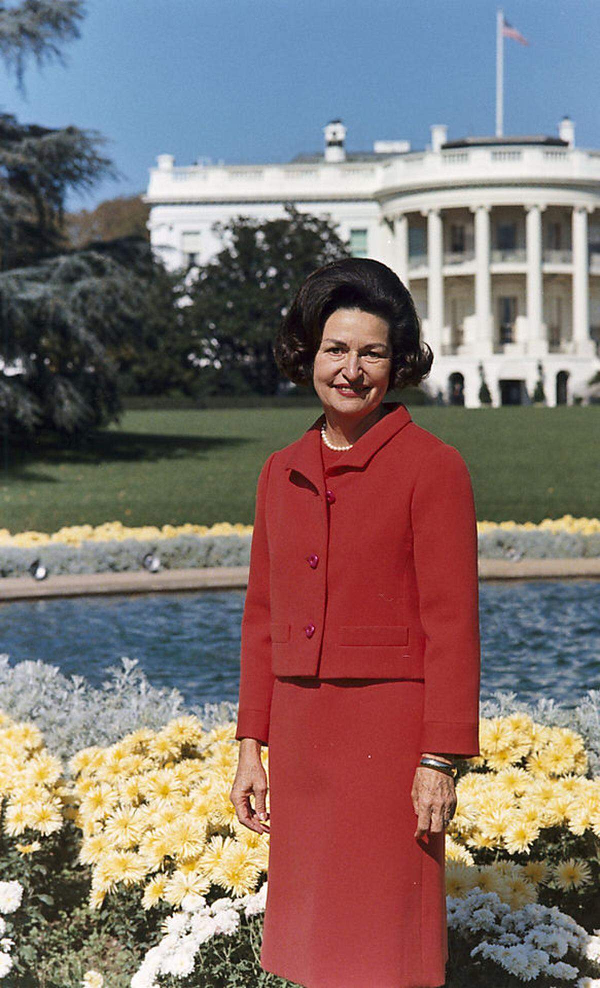 Für das offizielle Porträt verschlug es auch Lady Bird Johnson hinaus in die Gärten des Weißen Hauses an der Pennsylvania Avenue. Lady Bird Johnson wurde 1963 überraschend in die Position katapultiert - nach dem Mord an Präsident John F. Kennedy. Ihr Mann Lyndon B. Johnson war Kennedys Vizepräsident gewesen und folgte ihm somit nach. Johnson gewann die Wiederwahl zum Präsidenten 1964, er blieb bis 1969 im Amt. First Lady Johnson gab der Rolle der First Lady administrativ eine moderne Struktur - mit professionellem Presseteam und Büroleitung.