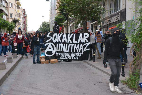 Im Vorfeld der Proteste warnte der Premier Recep Tayyip Erdogan vor einer Teilnahme. Obwohl die Demonstration am Taksim-Platz – dem Mittelpunkt der Gezi-Proteste – angemeldet war, wurde die Versammlung untersagt. Die Demonstranten trafen sich an verschiedenen Treffpunkten in den Seitenstraßen, organisiert wurde vor allem auch über Twitter. Zu einem großen Demonstrationszug wie vor einem Jahr kam es daher kaum. Im Bild: Vermummte Demonstranten mit dem Transparent „Die Straßen vergessen nicht“ - in Erinnerung an die Proteste im vergangenen Jahr.