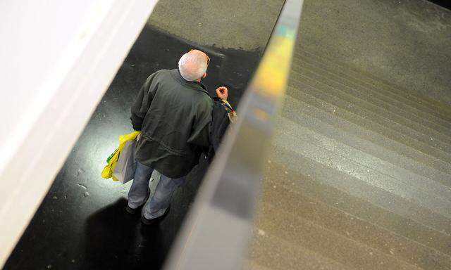 Alter Mann auf Rolltreppe