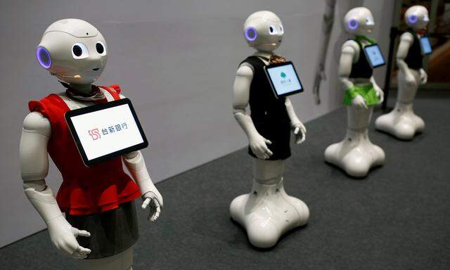 SoftBank´s robots ´pepper´, dressed in different bank uniforms, are displayed during a news conference in Taipei