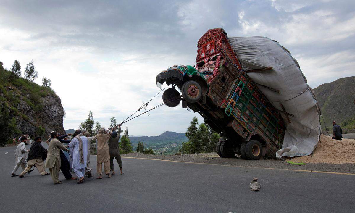 13. April 2012. Als hätte sich der Wagen aufgebäumt. Männer versuchten den mit Stroh überladenen Kleinlaster in Pakistan mit Seilen abzusichern.
