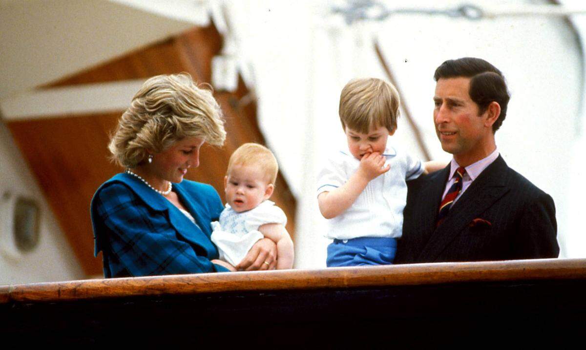 Prinz Harry wird  also zum ersten Mal Vater - „im Frühling“, wie der Kensington-Platz verlautbaren ließ. Es kann sich also nur noch um wenige Wochen oder Tage handeln, bis bei Herzogin Meghan, die sich bereits in der Babypause befindet, die Wehen einsetzen. Auf diesem Bild ist Prinz Harry gut behütet als Baby in den Armen von seiner Mutter, Prinzessin Diana, zu sehen. Bruder William und Papa Charles komplettieren das Familienfoto aus dem Jahr 1985.