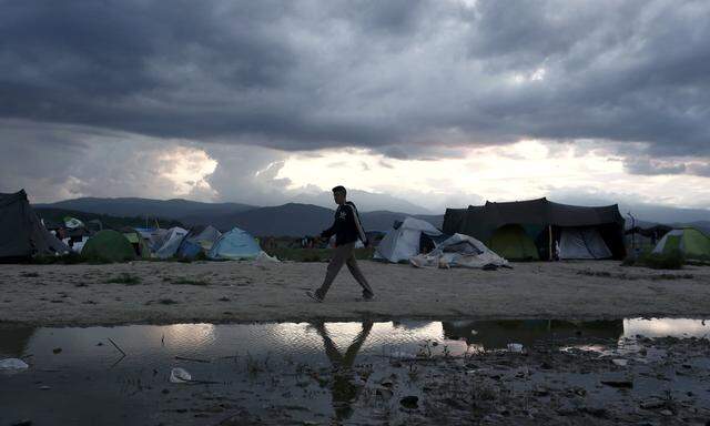 A young man makes his way next to tents at a makeshift camp for refugees and migrants at the Greek-Macedonian border near the village of Idomeni