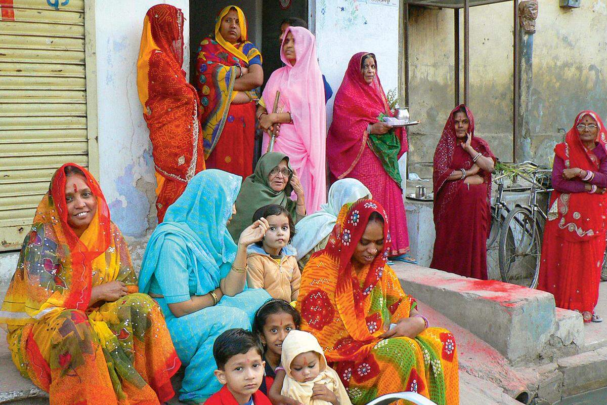 Frauen in leuchtend bunten Saris in Erwartung von noch mehr Farbe.