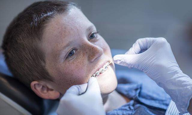 Boy with braces in dental surgery receiving dental floss treatment model released Symbolfoto propert