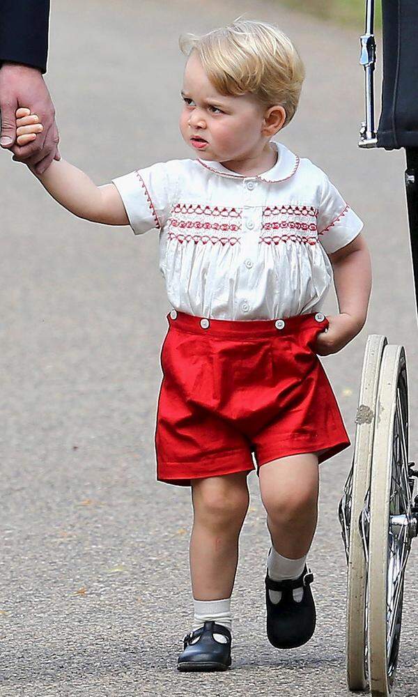 Oft trägt der Mini-Royal Kleidung, die schon sein Vater William in seinem Alter anhatte. Zur Taufe seiner kleinen Schwester Charlotte im Juli 2015 stahl er allen in knallroten Shorts, weißen Söckchen und einem bestickten Hemd die Show.