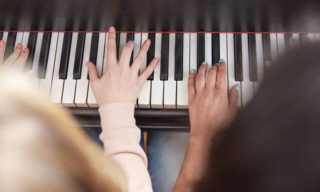 Close up of two girls playing piano together model released Symbolfoto property released PUBLICATION