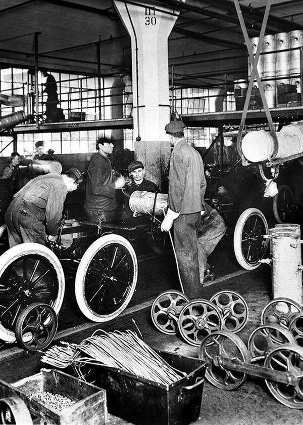 Aufnahme mit Arbeitern am Model T aus dem Jahr 1913: Henry Ford führt in seinem Werk in Detroit die Fließbandproduktion ein: „Die Geburtsstunde der modernen Autoindustrie.“ 