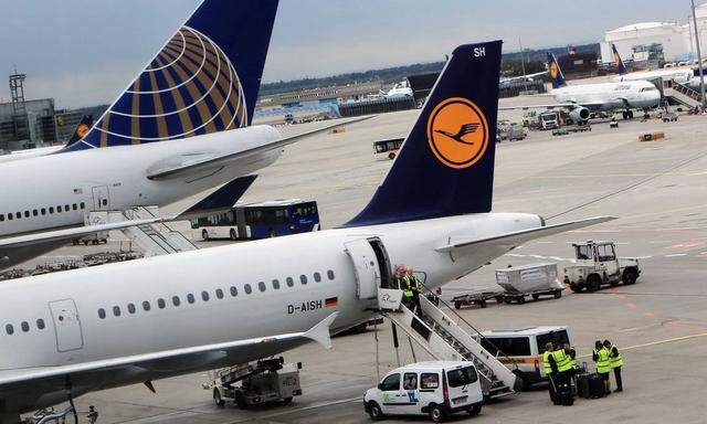 Flugzeuge der Lufthansa stehen auf dem Rollfeld und am Gate des Frankfurter Flughafens Leitwerke von