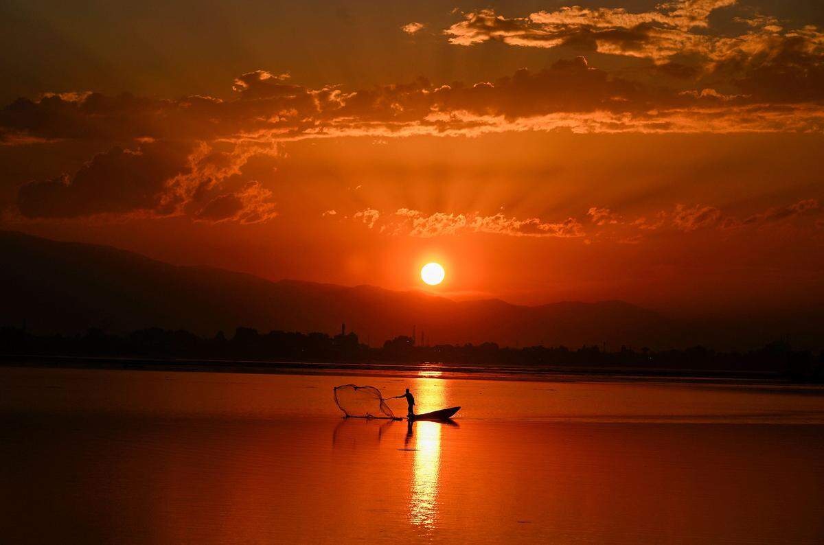 28. September. Ein Fischer wirft bei Sonnenuntergang sein Netz im Dal-See nahe der indischen Stadt Srinagar aus.