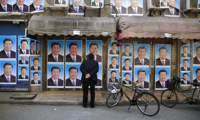 A man looks at a building covered in posters of Chinese President Xi Jinping in Shanghai