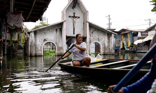 Eine Frau paddelt nach einer Überflutung im Sommer durch die Straßen des philippinischen Malabon.