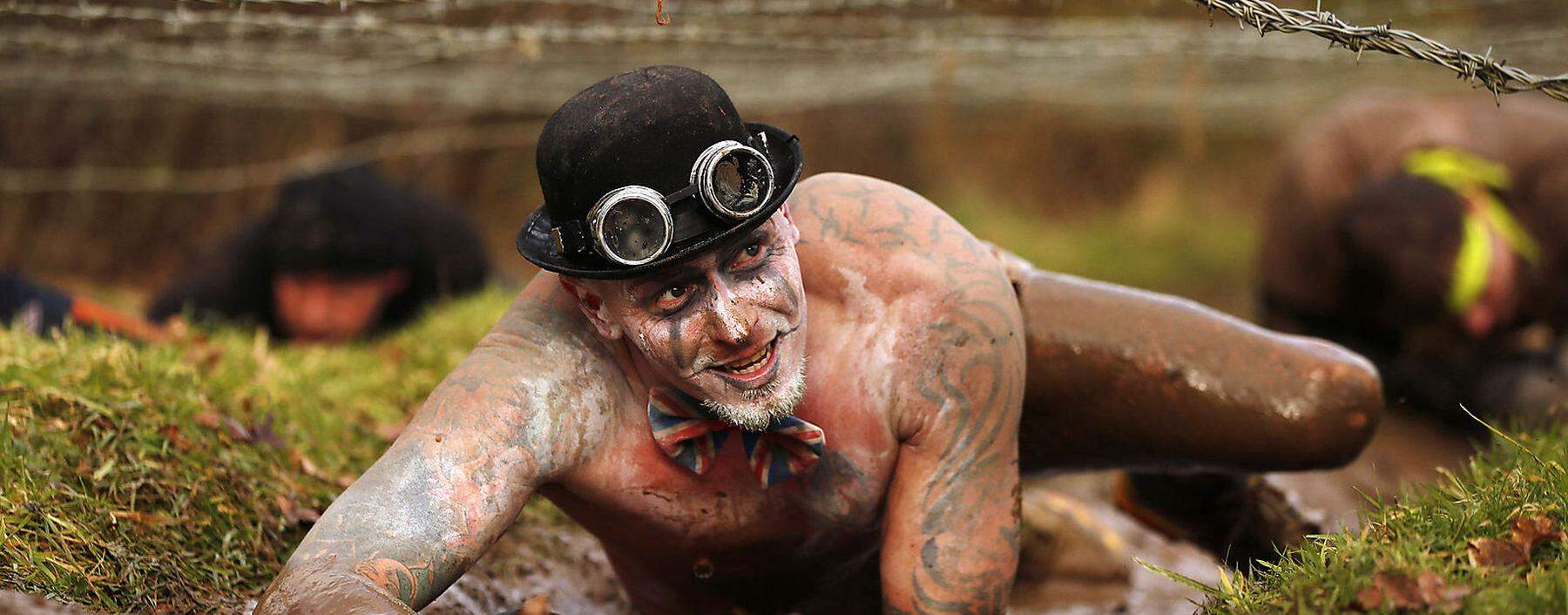 A competitor crawls beneath barbed wire during the Tough Guy event in Perton, central England