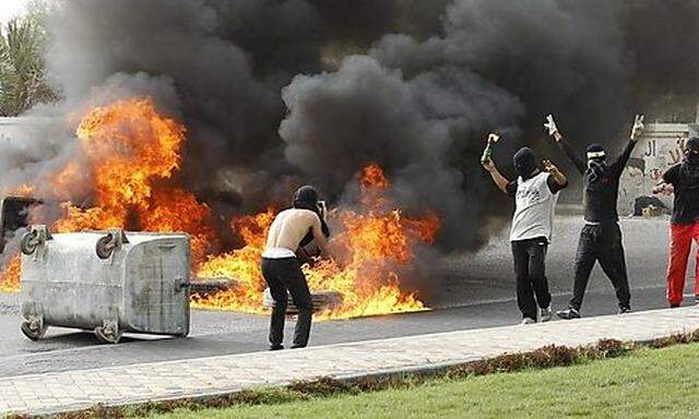 Anti-government protesters flash victory signs as they burn tires in Budaiya