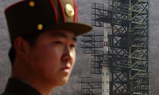 File photo of a soldier standing guard in front of the Unha-3 (Milky Way 3) rocket sitting on a launc