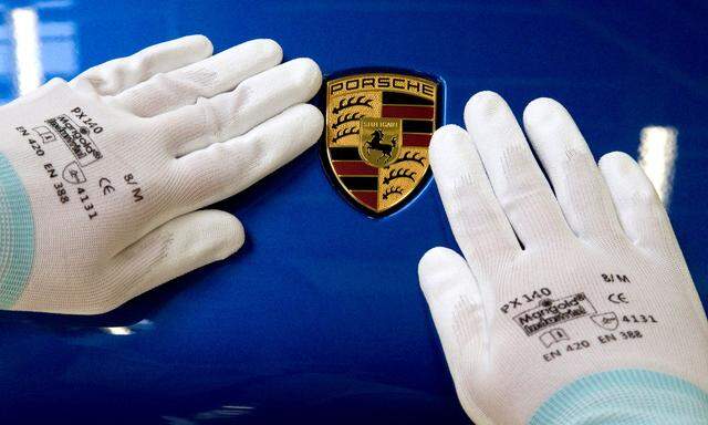 FILE PHOTO: A man does the final touches on the Porsche logo of a Macan at the plant in Leipzig