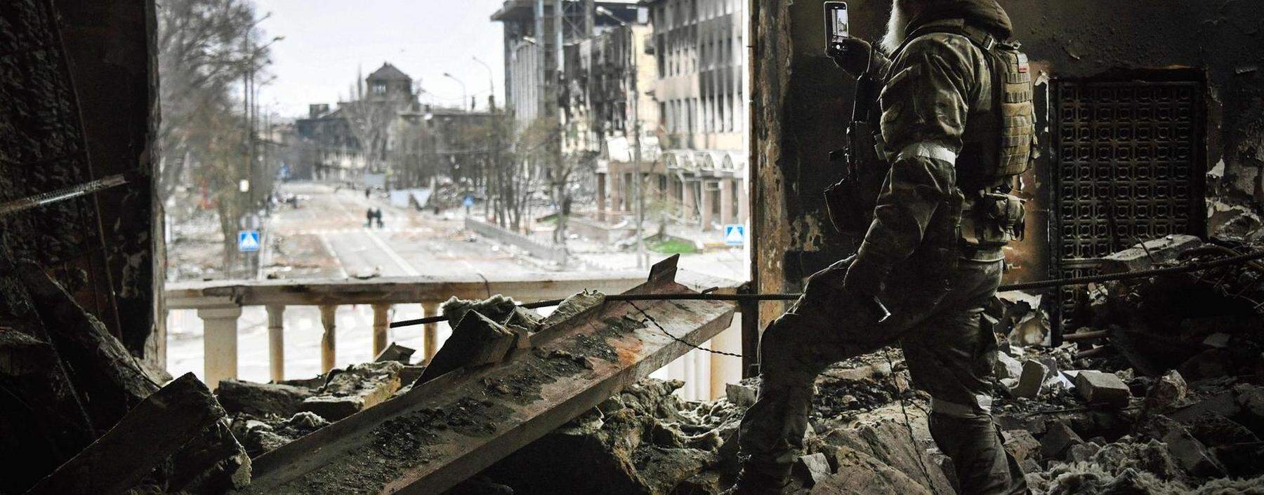 Ein russischer Soldat fotografiert die Ruinen des Theaters in Mariupol. Obwohl hier eindeutig Zivilisten Zuflucht gesucht hatten, wurde das Gebäude im März bombardiert. Die Anzahl der Opfer ist unklar. 
