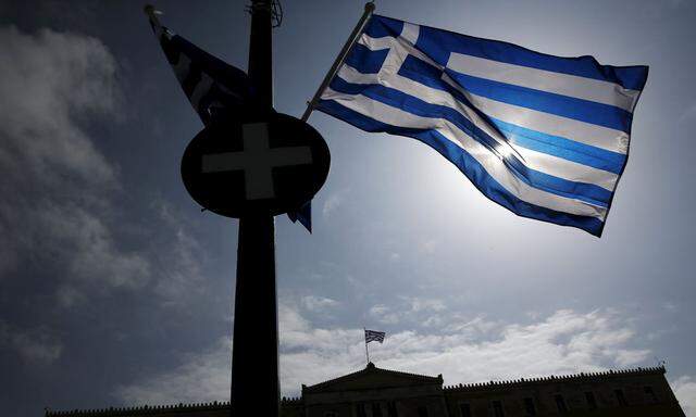 A Greek national flag flutters as the parliament building is seen in the background in Athens 