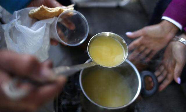 Spanish Luis Dominguez Quintana, a member of the Mortgage Victims' Platform, puts vegetable soup in a plastic cup outside the nationalized lender Bankia bank headquarters in Madrid