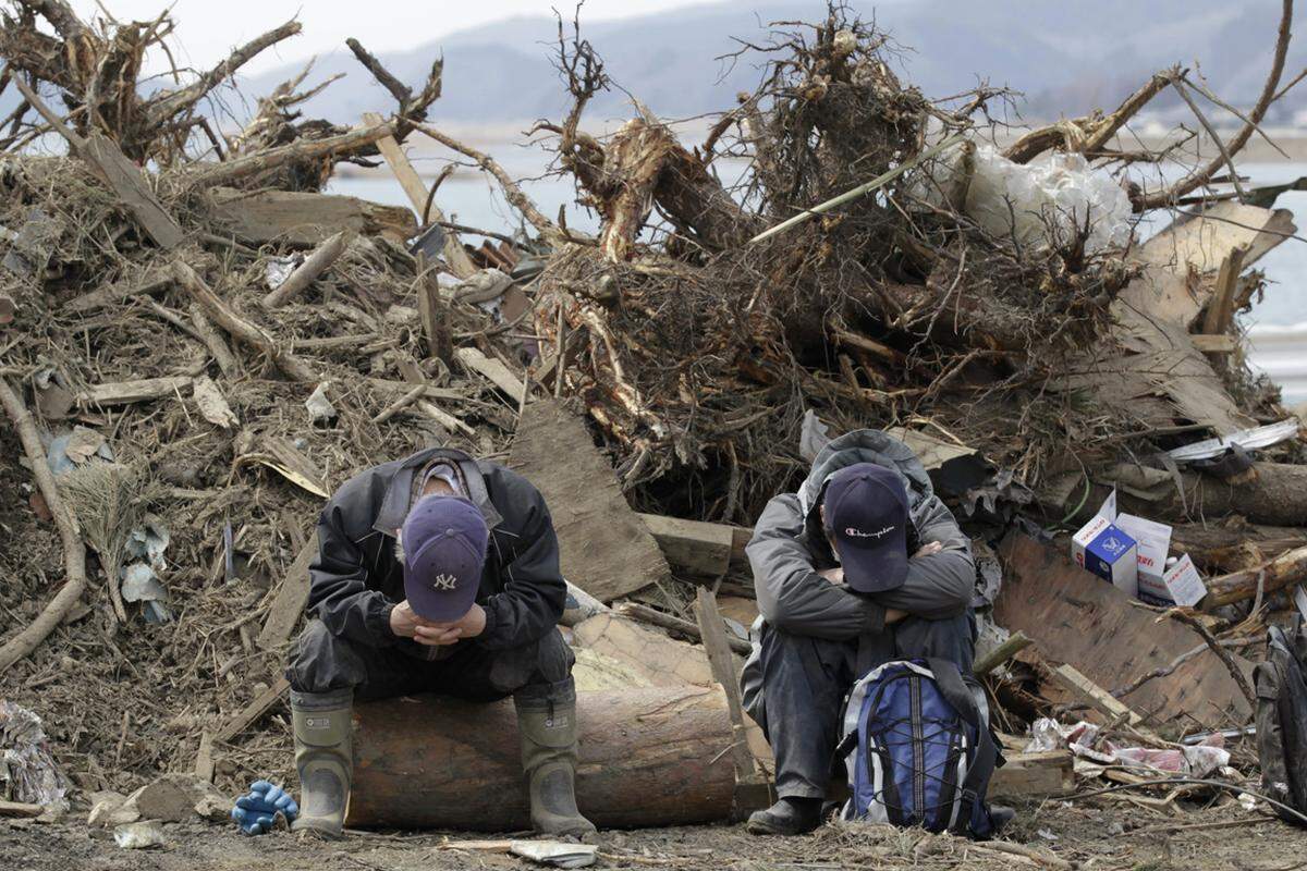 Nahe der Okawa-Volksschule sitzen zwei Anwohner mit gesenkten Köpfen. Nur 34 der 108 Schüler haben die Katastrophe überlebt. (29. März)
