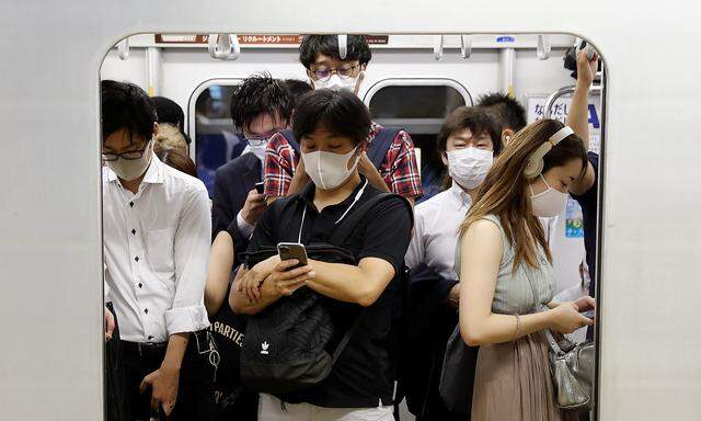 Passengers wearing protective masks amid the coronavirus disease (COVID-19) outbreak, ride a subway train in Tokyo