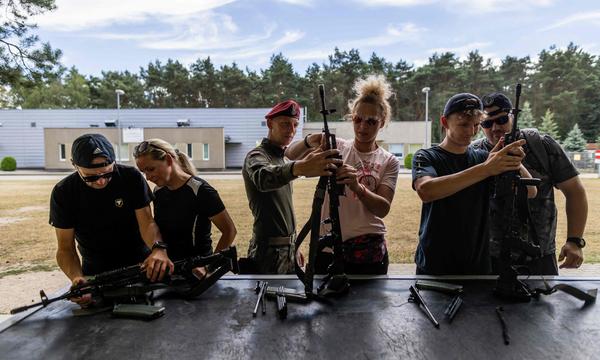 Angehörige der polnischen Armee instruieren Zivilisten im Umgang mit der Waffe.