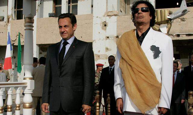 FILE PHOTO: Libya´s President  Gaddafi and his counterpart from France Sarkozy listen to national anthems at Bab Azizia Palace in Tripoli