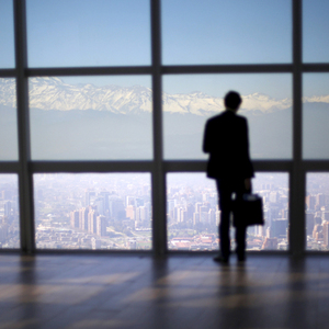 A man looks out to the Los Andes mountain range next to the city from a rooftop of a commercial center