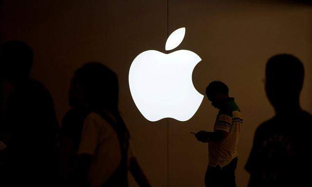 FILE PHOTO: A man looks at the screen of his mobile phone in front of an Apple logo outside its store in Shanghai