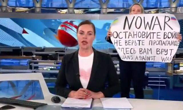 Widerstand im russischen Staatsfernsehen: Im Hintergrund ist die Frau mit ihrem Plakat zu sehen. Sie soll selbst beim Fernsehsender gearbeitet haben, der sich freilich streng an die Kreml-Linie hält.