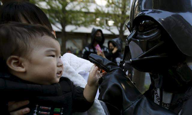 A boy looks at his father dressed up as Darth Vader from ´Star Wars´ during a Star Wars parade, which is part of a Halloween parade in Kawasaki