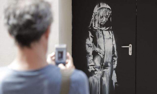 Archivbild: Ein Mann macht am 25. Juni 2018 in Paris ein Foto des Straßenkünstlers Banksy in einer Seitenstraße zum Konzertsaal Bataclan.