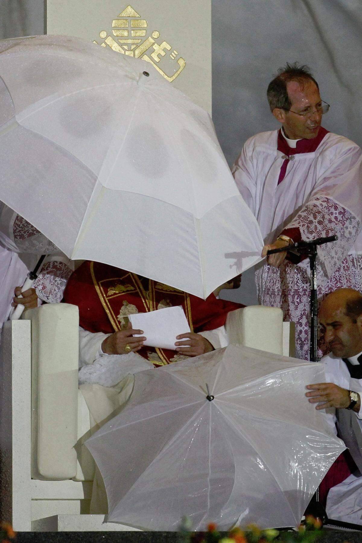 Plötzliche heftige Windstöße rissen kurz nach dem Beginn der Predigt die weiße Kopfbedeckung des Papstes fort. Der 84-Jährige griff mit zerwühltem Haar nach seinem durchnässten Manuskript und zog sich unter einen größeren Schirm zurück.