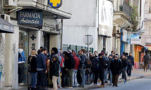People queue in line outside of a pharmacy to buy legal marijuana in Montevideo