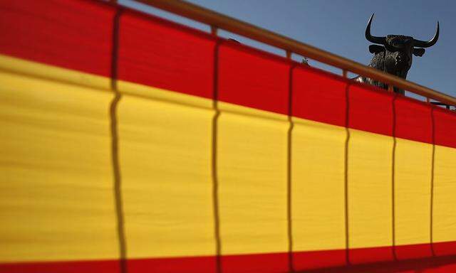 A statue of a bull is seen next to a Spanish flag on the eve of Spain's National Day in downtown Ronda