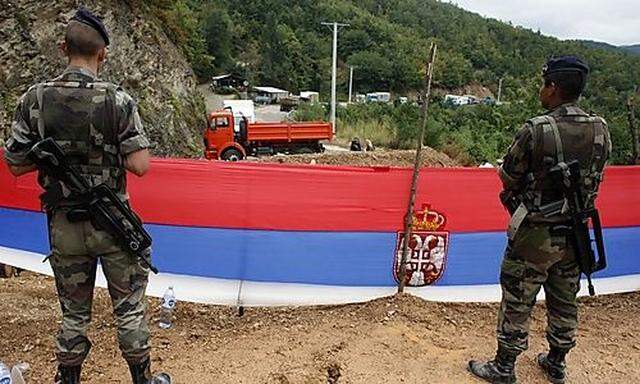 Serbian flag is seen as KFOR soldiers from France stand guard at the closed Serbia-Kosovo border cros